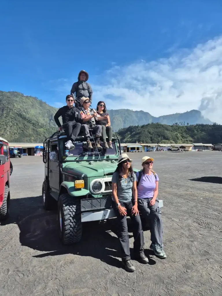 Jeep sunrise Bromo melaju di lautan pasir dengan latar Gunung Batok saat golden hour pagi